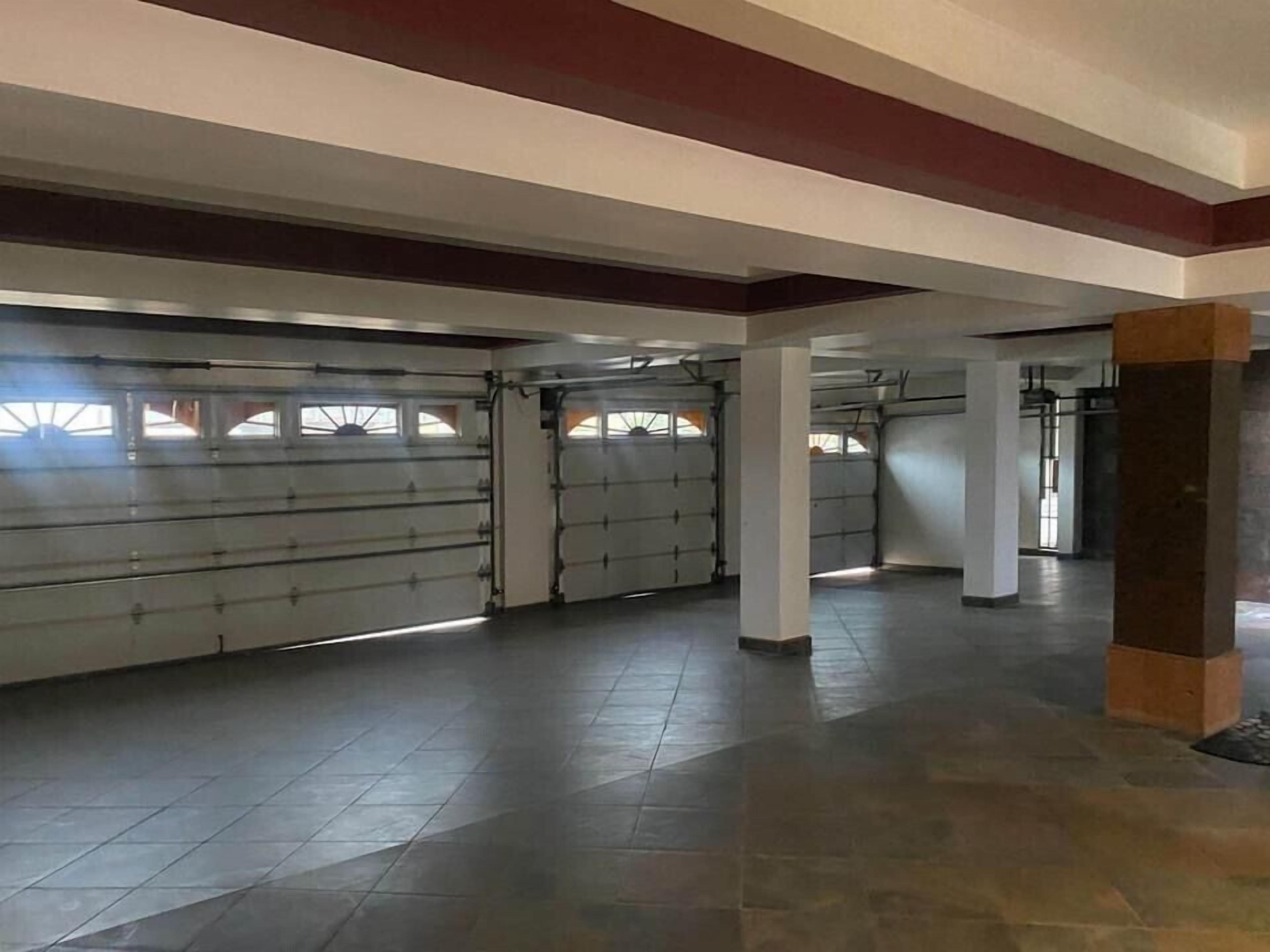 A spacious indoor area with a tiled floor, large windows, and a garage door.