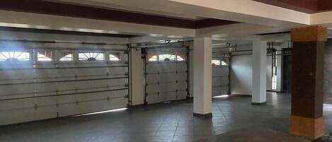 A spacious indoor area with a tiled floor, large windows, and a garage door.