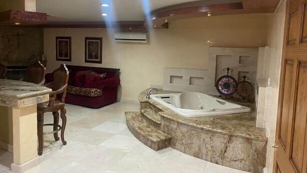 Un baño espacioso con tocador de mármol, una bañera independiente y un sofá rojo.