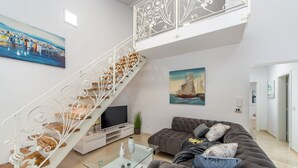 A spacious living area with a modern staircase, a comfortable sofa, a flat-screen TV, and a painting of a ship on the wall. - Villa Shaula 2 (Bilice)
