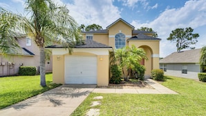 A residential house with a garage, a lawn, and a palm tree.