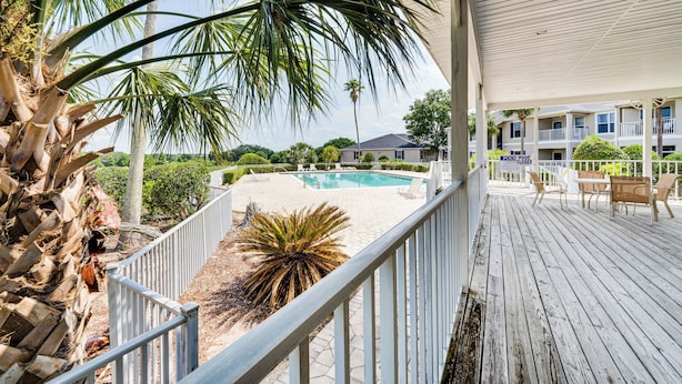 A wooden deck with a pool, palm trees, and a sign indicating the pool is closed.