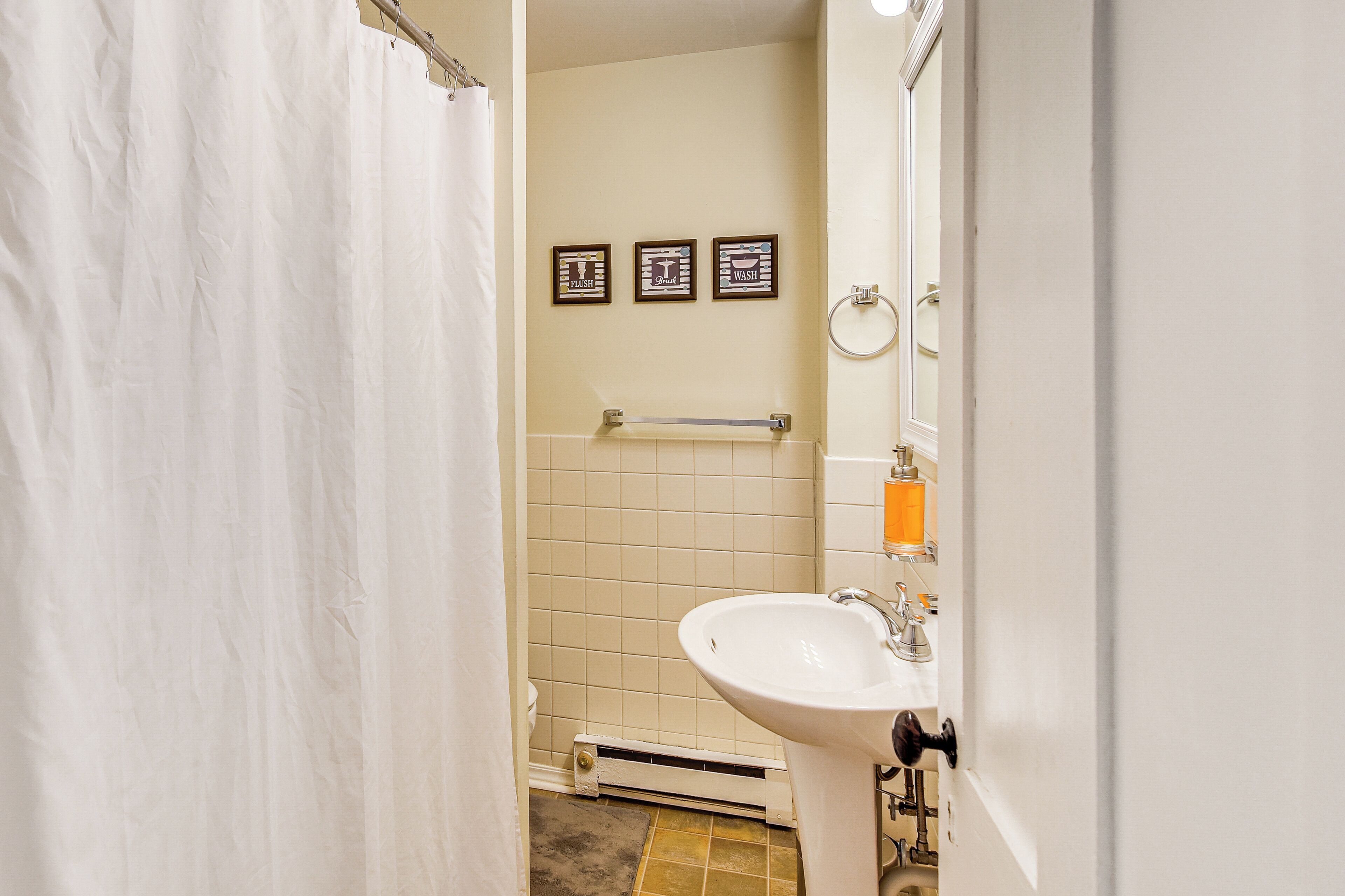 Ein Badezimmer mit einem weißen Waschbecken, einem Handtuchhalter und drei gerahmten Bildern an der Wand.