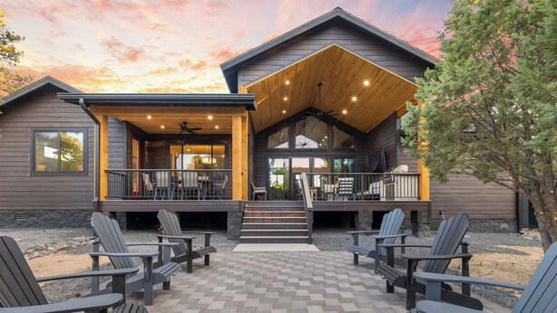 Een modern vakantiehuis met een overdekte patio, buitenmeubels en een groot houten terras.