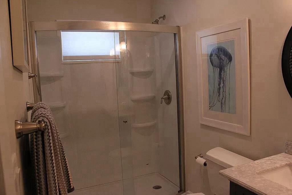 A bathroom with a glass-enclosed shower, a toilet, and a sink.