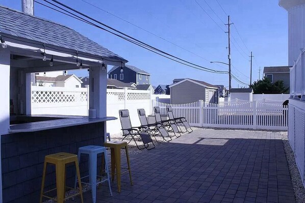 Eine Terrasse mit Bar, zwei Barhocker und einer Reihe von Stühlen.