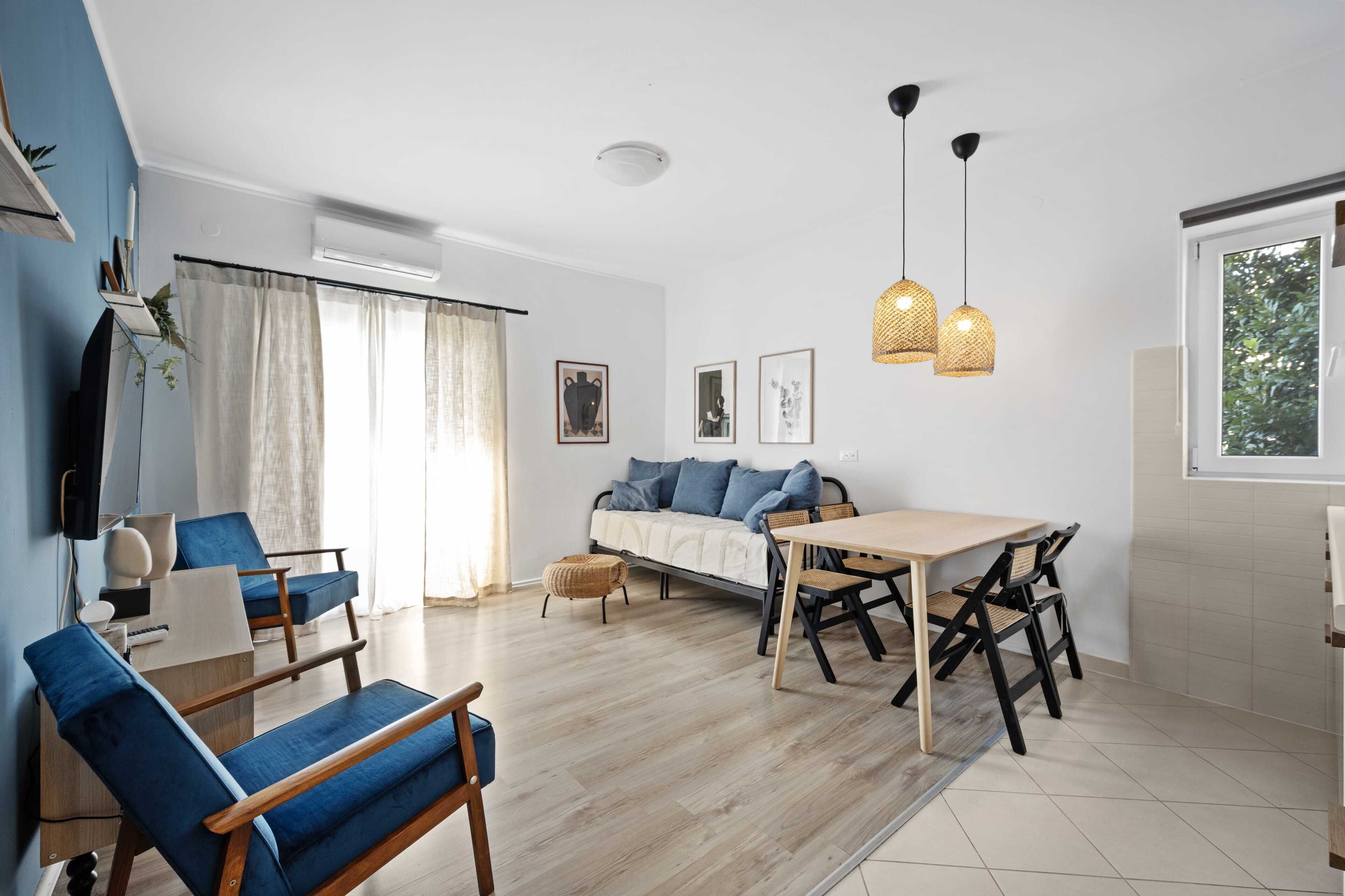 Un salon moderne avec un canapé, des fauteuils, une table à manger et des luminaires suspendus.