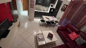 A modern living room with a red sofa, a coffee table, and a dining area with a table and chairs. - Charming 2-bedroom apartment with completed kitchen, nera Milano, Como and Swiss (Mozzate)