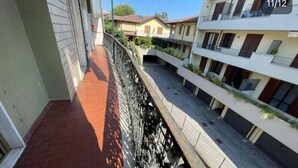 A multi-story residential building with balconies, a brick pathway, and a stone wall. - Charming 2-bedroom apartment with completed kitchen, nera Milano, Como and Swiss (Mozzate)