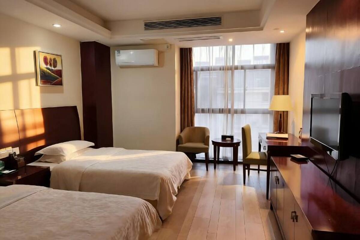 Une chambre d’hôtel avec deux lits, une télévision, un bureau et une chaise.