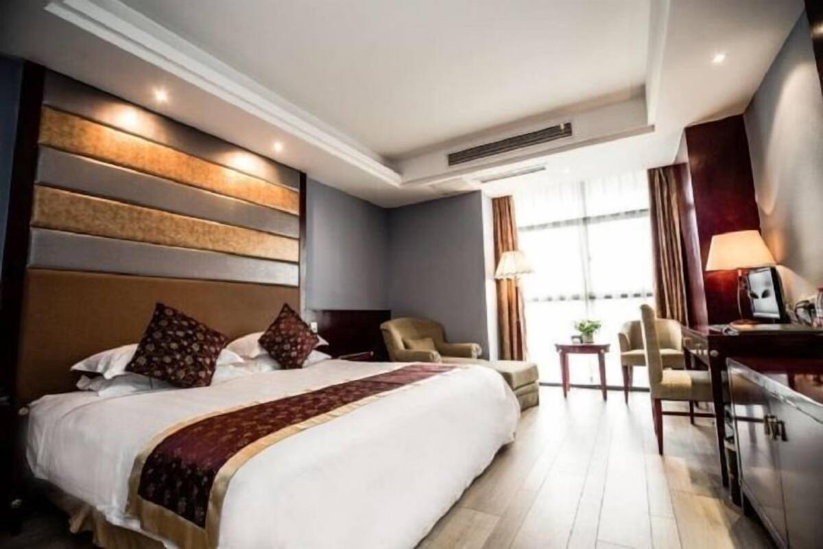Une chambre d’hôtel avec un grand lit, un bureau, une chaise et une vue sur l’extérieur.
