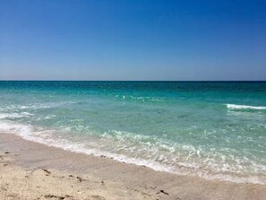A beach with clear turquoise water and a sandy shore.