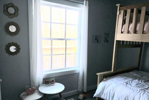 A bedroom with a bunk bed, a small round table with a plant, and decorative mirrors on the wall. - 3-bedroom house in charming Falls of Rough with WiFi, AC (Falls of Rough)