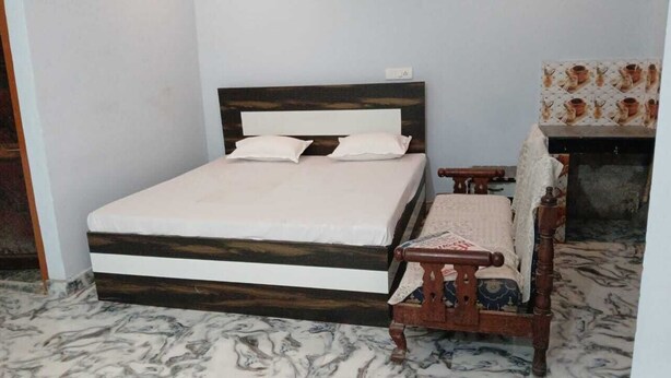 Un dormitorio con cama y silla de madera, y pared con baldosas.