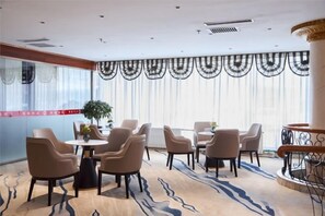 A hotel room with a dining area featuring round tables and chairs, a large window with curtains, and a view of the outside. - Harbin Gangcheng Hotel (Engineering University Subway Station) (Harbin)