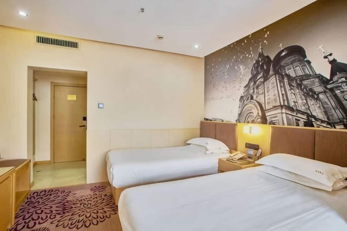 A hotel room with two beds, a wooden headboard, a nightstand, a telephone, and a wall mural.