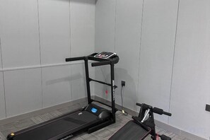 A treadmill in a room with a grey wall and a carpeted floor. - Harbin Gangcheng Hotel (Engineering University Subway Station) (Harbin)