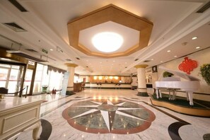 A spacious lobby with a central circular marble floor, a grand piano, and a reception desk. - Harbin Gangcheng Hotel (Engineering University Subway Station) (Harbin)