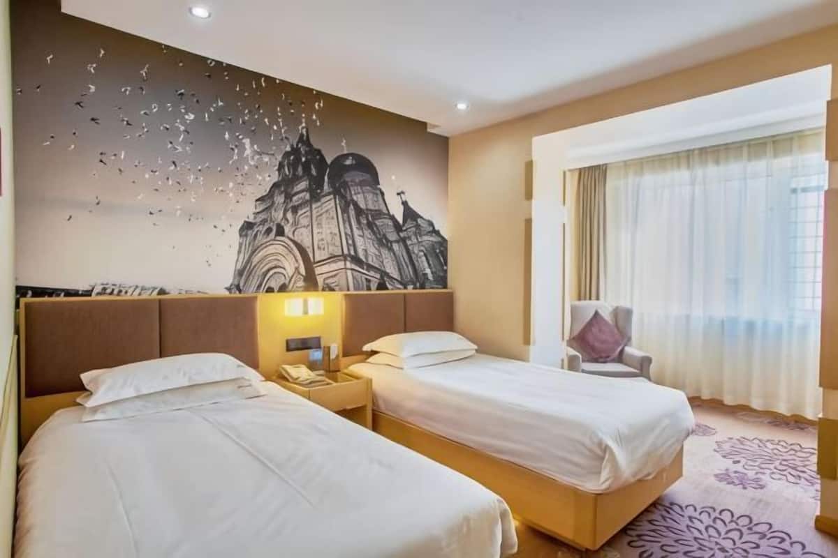 A hotel room with two beds, a nightstand with a phone, a chair, and a large window with curtains.