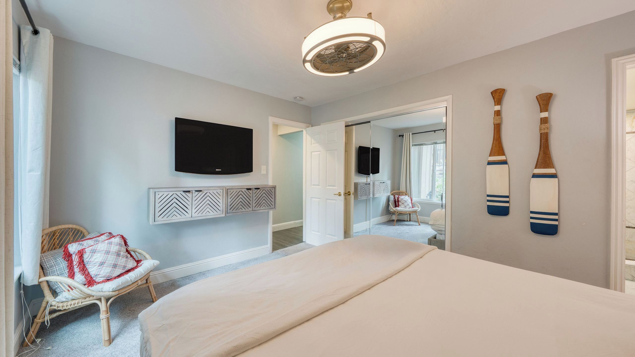Ein Schlafzimmer mit einem Bett, einem Fernseher, einem Sessel und zwei Surfbrettern an der Wand.
