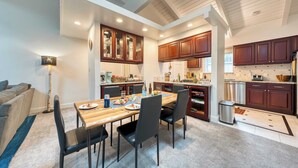 A modern kitchen with wooden cabinets, a dining table with chairs, and a built-in oven.