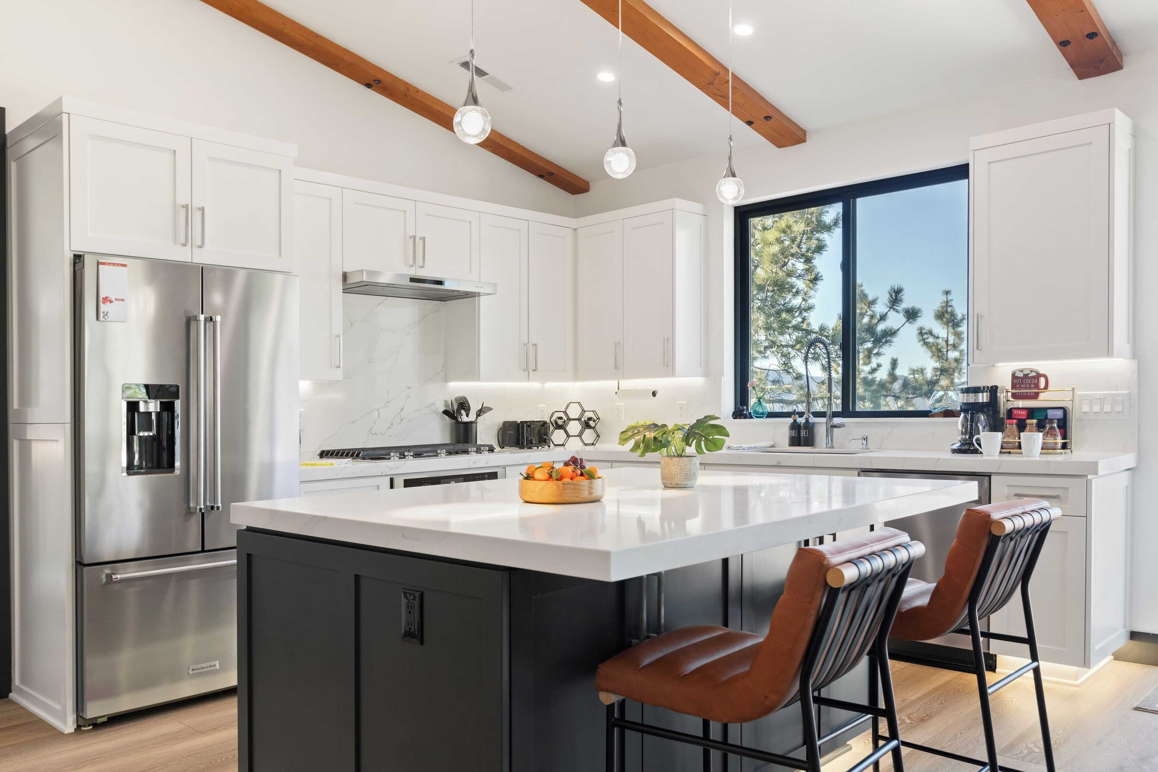 A modern kitchen with white cabinets, stainless steel appliances, and a large island with bar stools.