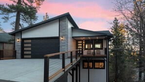 A modern two-story house with a garage, a balcony, and a stone facade.