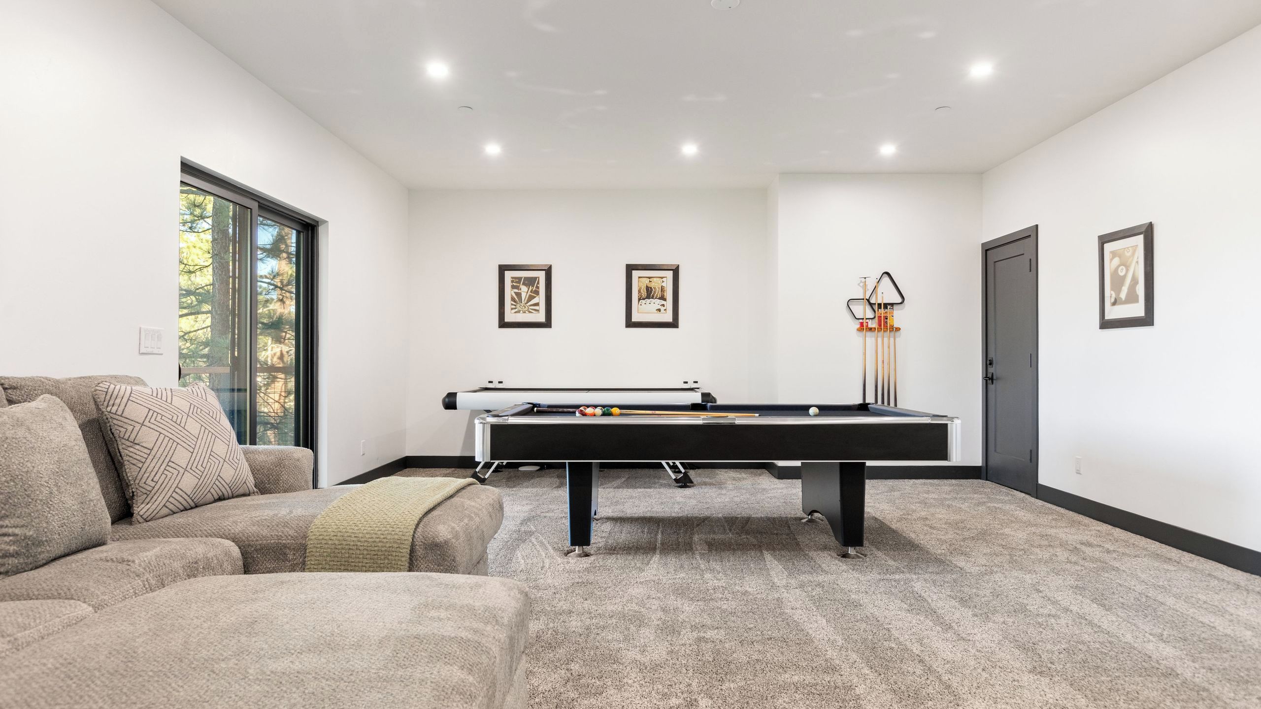 A modern room with a pool table, a sofa, and a door.
