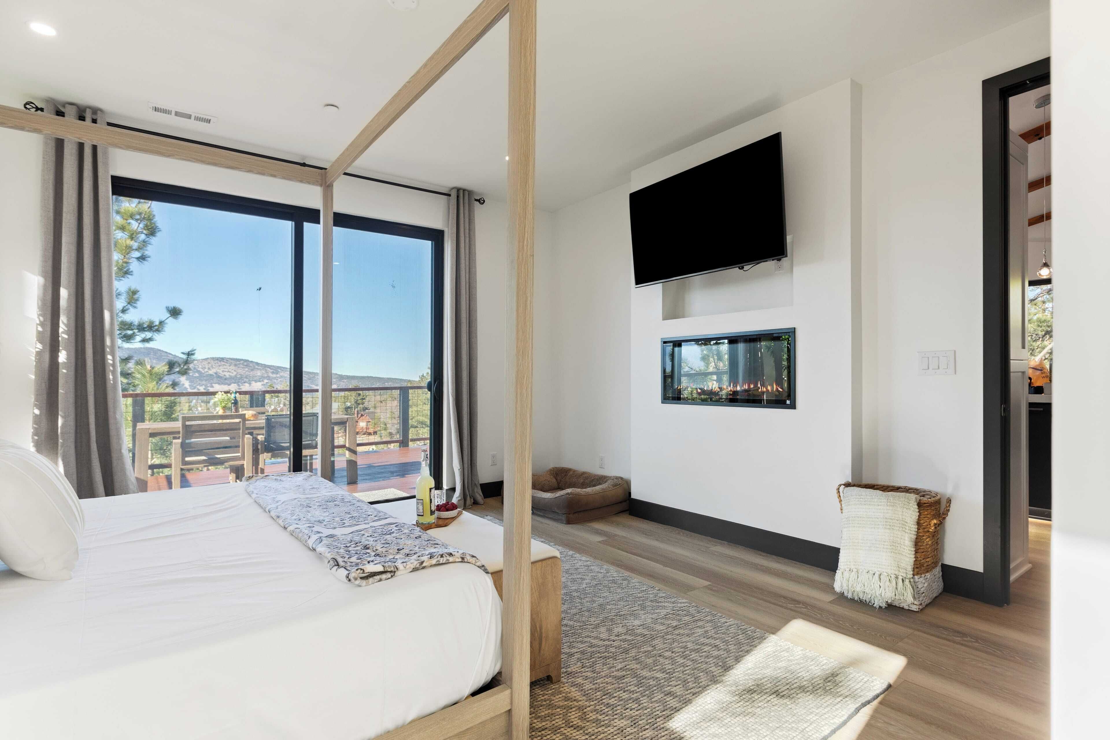 Een moderne slaapkamer met een groot bed, een aan de muur bevestigde televisie en uitzicht op de omgeving.