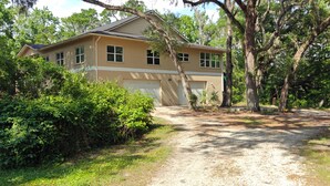 A two-story house with a garage, surrounded by dense greenery and trees. - Wise Owl Retreat, a beautiful suite amongst towering oaks, access to River/view. (Dunnellon)