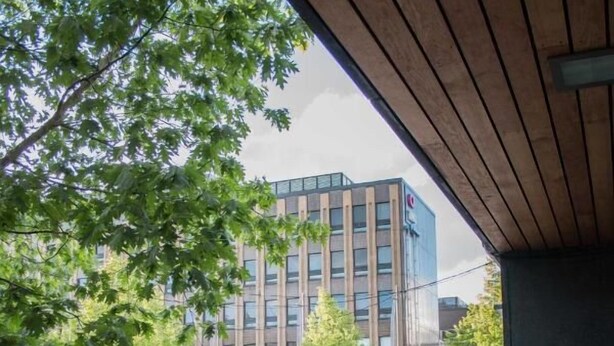 Une vue urbaine avec un bâtiment moderne, des arbres et un parterre de fleurs.