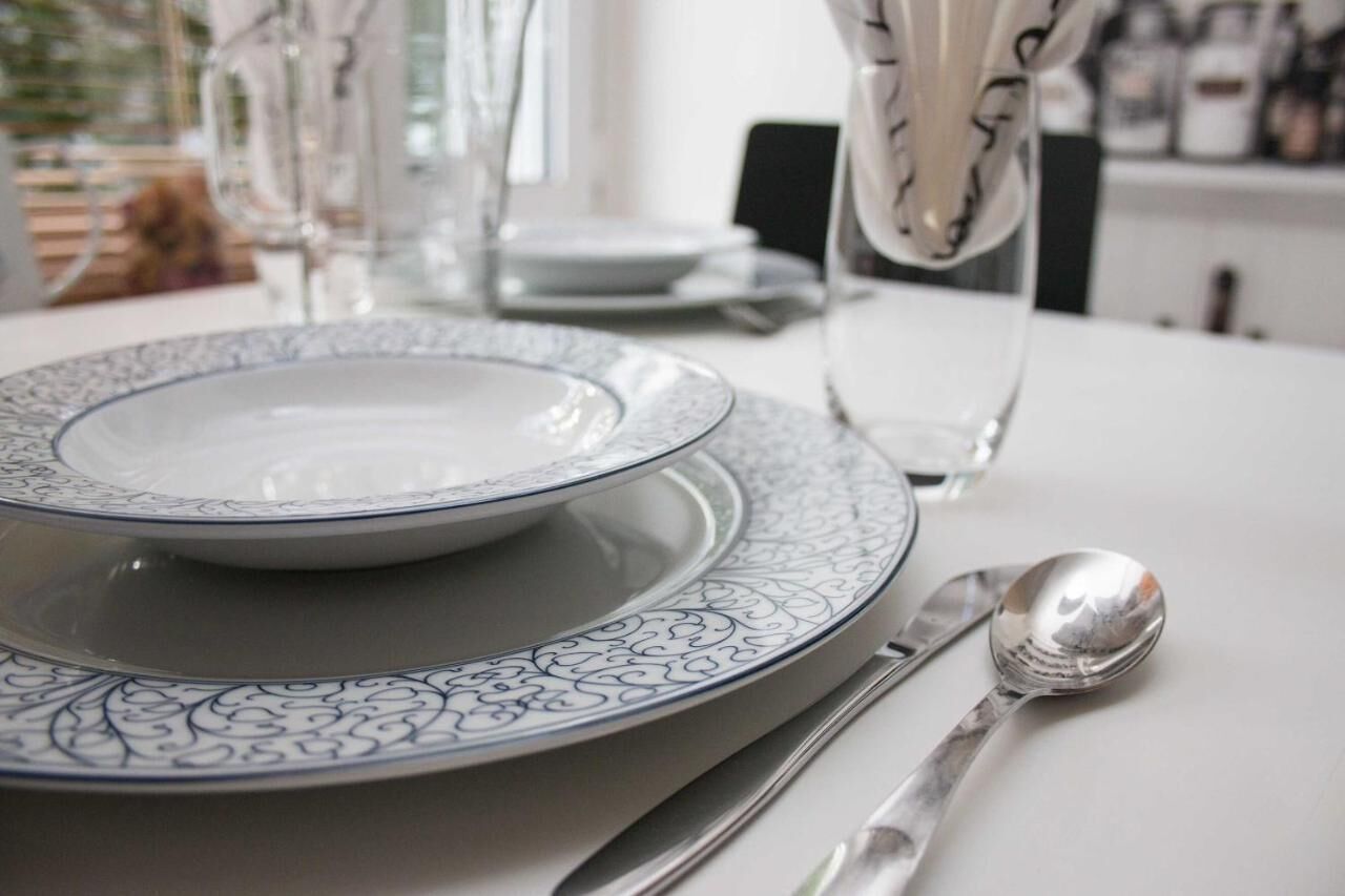 A dining table set with plates, a spoon, and a vase.