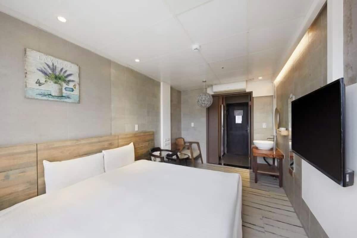 Une chambre d’hôtel avec un grand lit, une télévision, une petite table et une chaise.