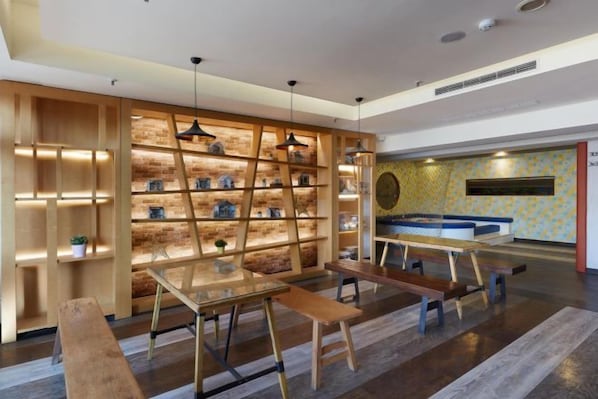 Un interior moderno con una estantería de madera, un comedor con bancos y un papel tapiz estampado.