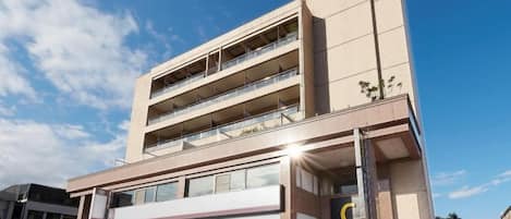 Un edificio de varios pisos con un llamativo logo en forma de 'C', ventanas amplias y balcones.