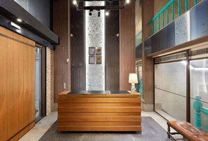 A reception area with a wooden reception desk, a stone accent wall, and a teal railing.