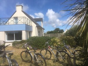 Um bairro residencial com uma casa, bicicletas e um jardim.