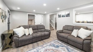A modern living room with two grey sofas, a patterned rug, and a staircase leading to another room. - Newly Renovated 4 bedroom home (West Valley City)
