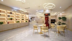 Una hall d'albergo moderna con reception, area salotto e illuminazione decorativa.