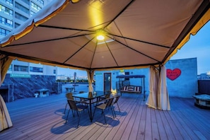An outdoor patio with a table and chairs under a large umbrella, a barbecue grill, and a heart-shaped decoration on the wall. - Xi'an Sende Hotel (Chang'an University Wenyi Road Metro Station Branch), (Xi'an)
