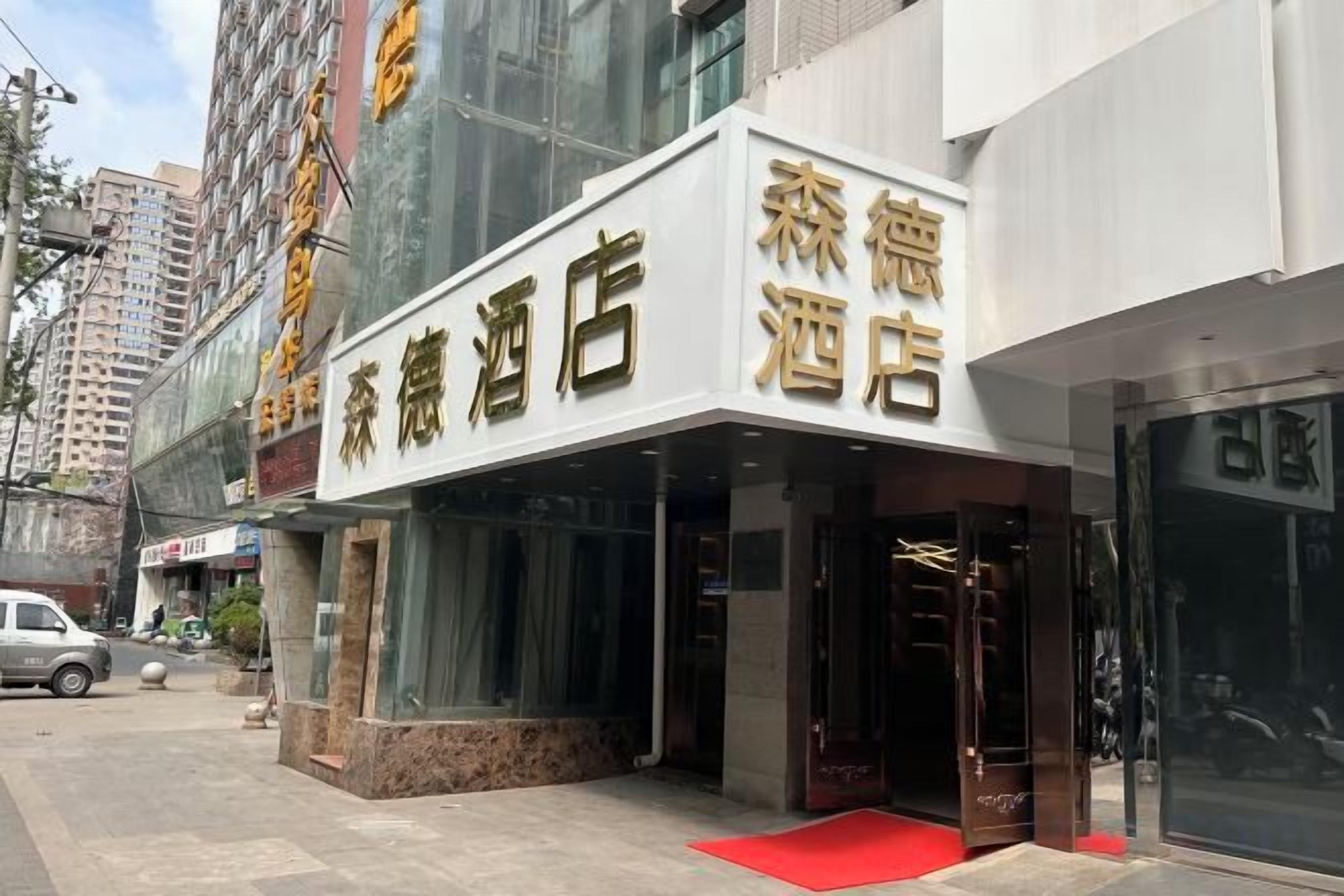 A hotel entrance with a red carpet, glass doors, and a sign indicating it is a hotel.