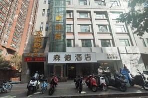 A hotel with a signboard, several parked scooters, and a tall building in the background. - Xi'an Sende Hotel (Chang'an University Wenyi Road Metro Station Branch), (Xi'an)