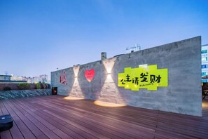 A rooftop terrace with a concrete wall featuring a heart-shaped cutout and a yellow sign with Chinese characters. - Xi'an Sende Hotel (Chang'an University Wenyi Road Metro Station Branch), (Xi'an)