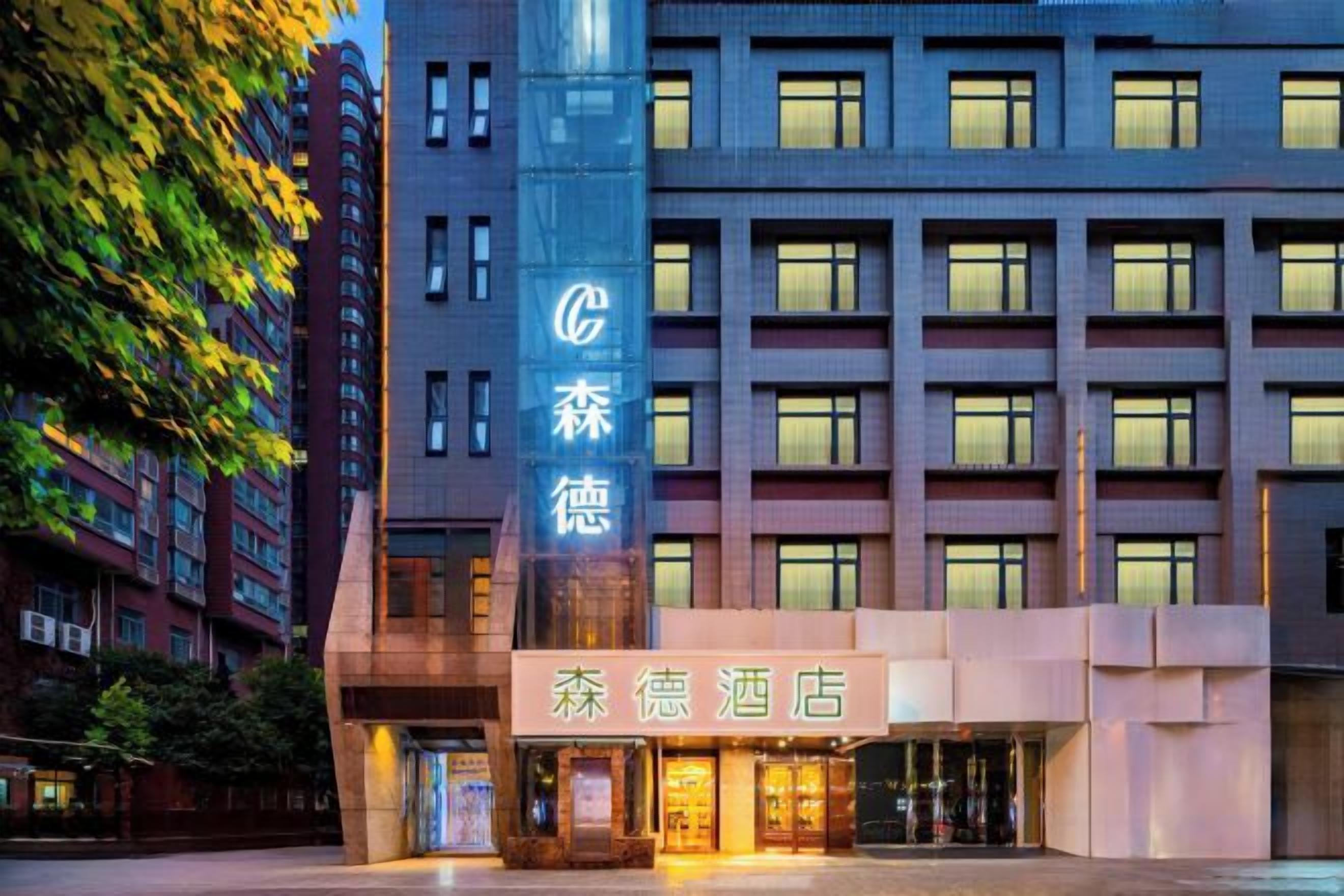 A hotel with a prominent vertical sign and a well-lit entrance.