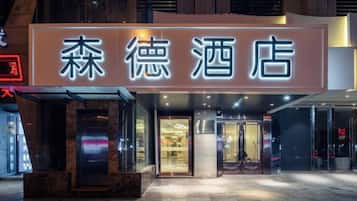 A hotel entrance with a sign in Chinese characters, a glass door, and a modern facade.