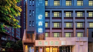 Un hotel con un cartello verticale ben visibile e un ingresso segnalato da un'insegna orizzontale.