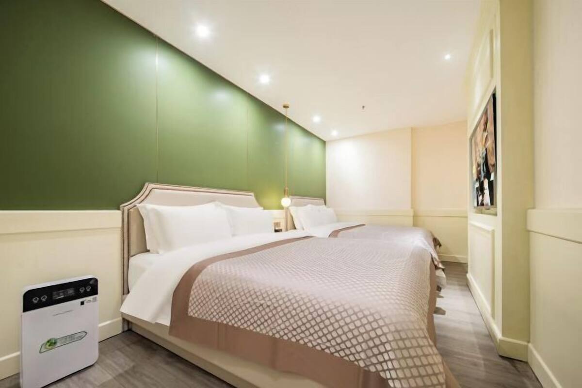 A hotel room with a bed, a heater, and a wall-mounted picture.