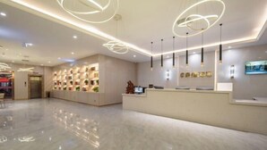 Una hall d'albergo moderna con una reception, un'area salotto e un grande lampadario circolare.