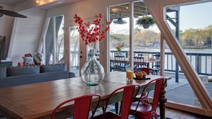 A dining area with a wooden table, red chairs, and a vase with red flowers.