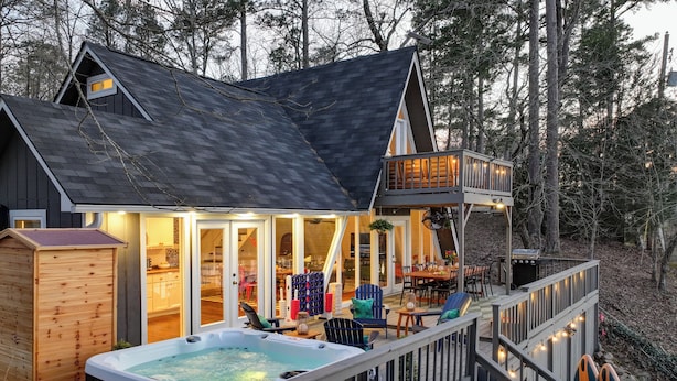 A cabin with a hot tub, deck, and a covered outdoor seating area.